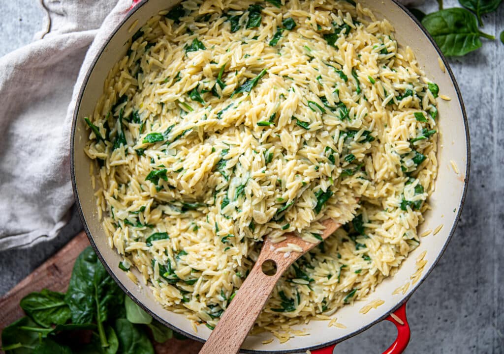 A large pot with creamy parmesan orzo with lots of spinach.  