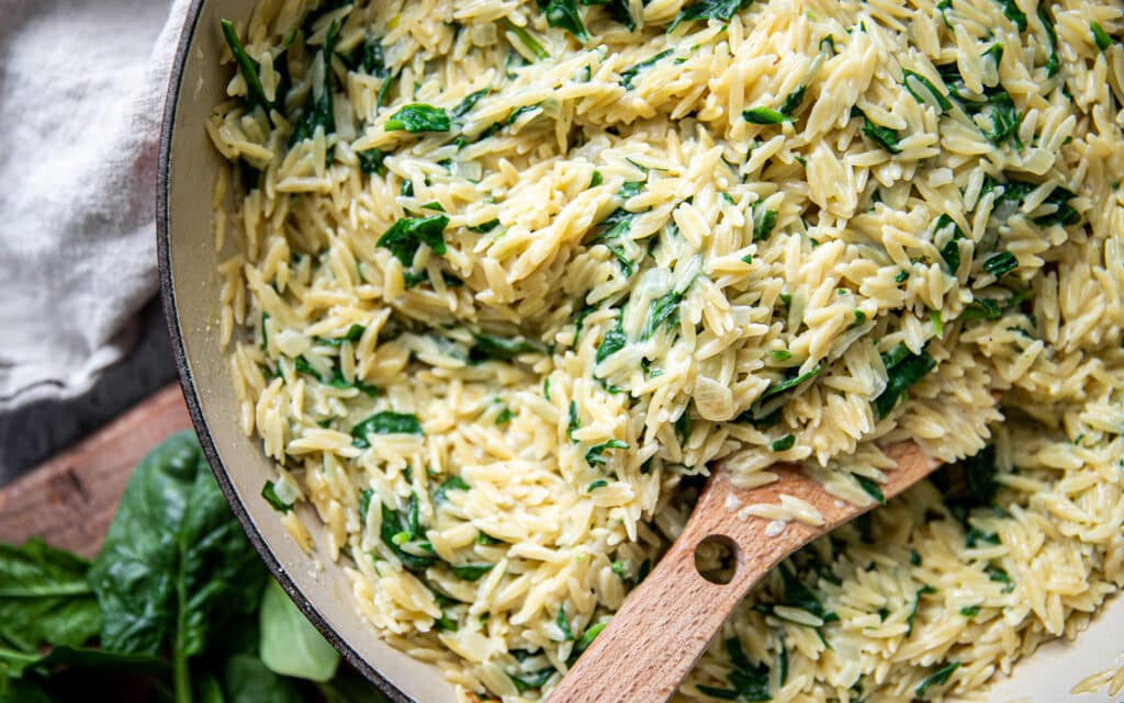 A pot of creamy parmesan orzo with lots of spinach.  